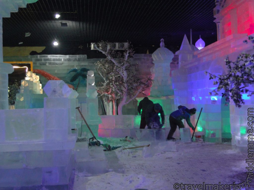 Workers cut and stack large blocks of ice indoors to make ice sculptures