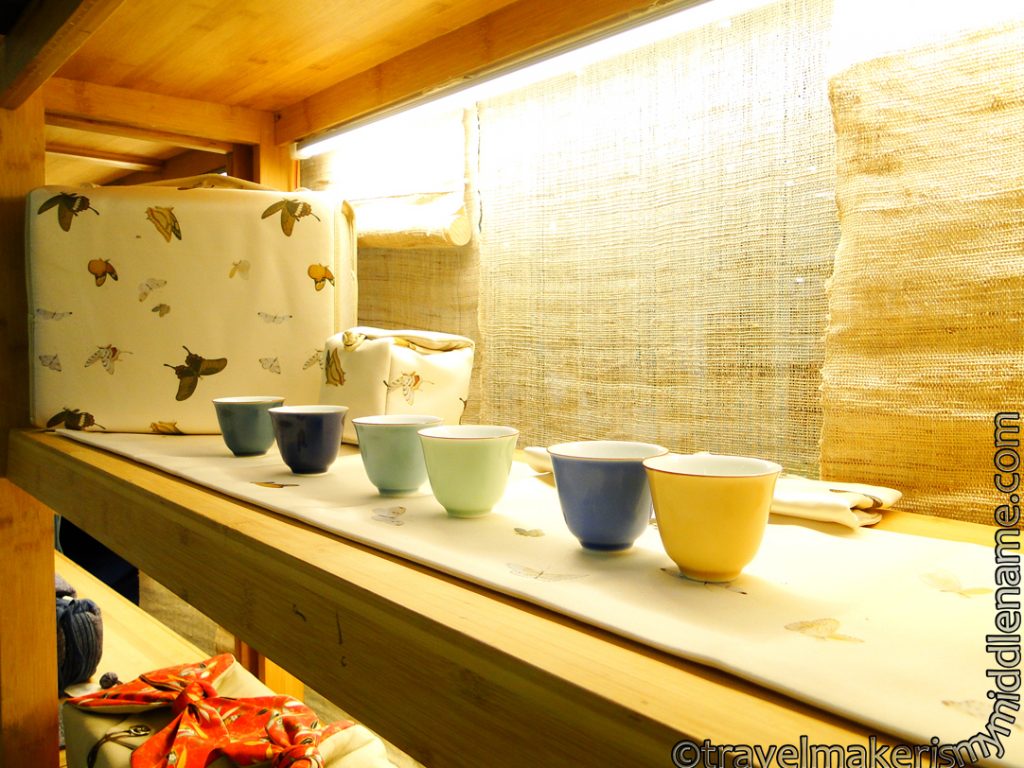 A row of tea cups in various neutral toned colours: yellow, blue, green, brown.