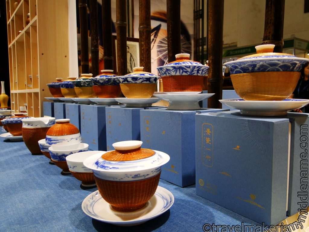 White and blue ceramic tea cups with woven bamboo holders and lids.