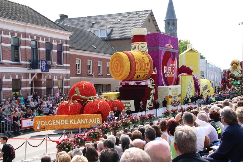 A long parade float shaped like giant grocery products: tomatoes, cartons and jars of food.