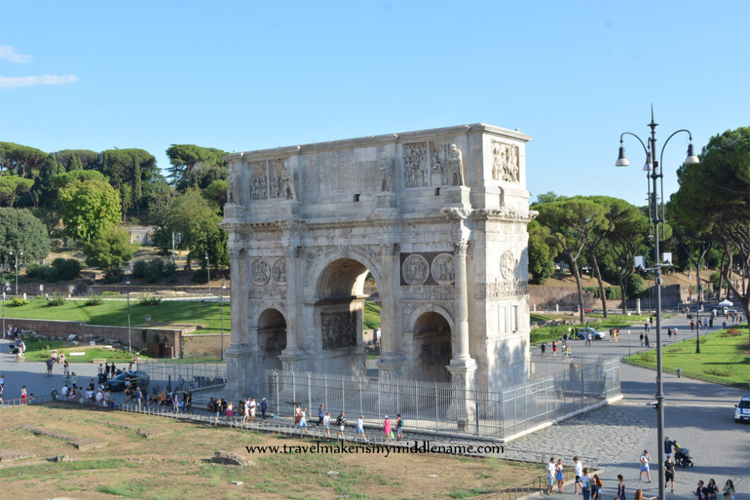 The Arch of Constantine in Rome, Italy during the day against a cloudless blue summer sky.