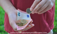 Person holding a 10 Euro note and some coins.
