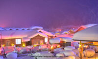 Meng Huan Jia Yuan village at night with many "snow mushrooms": round pillows of white snow that collect on top of stumps of wood, and wooden houses covered in snow looks exactly like a gingerbread house covered in sugar icing.