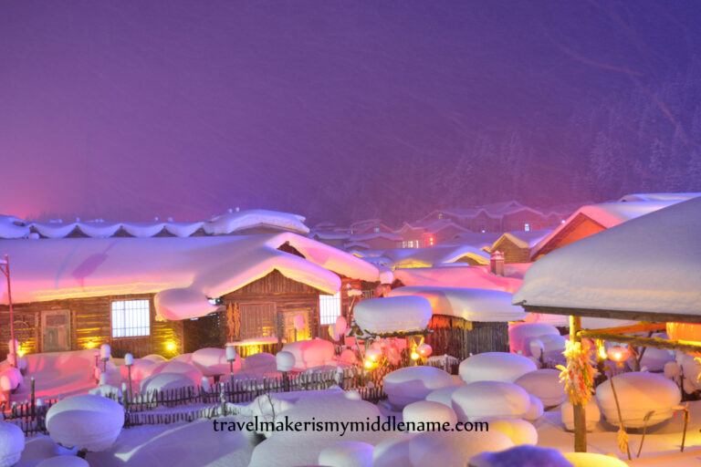 Meng Huan Jia Yuan village at night with many "snow mushrooms": round pillows of white snow that collect on top of stumps of wood, and wooden houses covered in snow looks exactly like a gingerbread house covered in sugar icing.