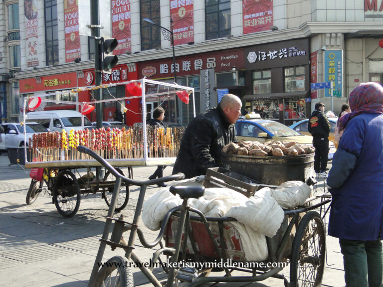 A cart selling bing tang hulu (skewers of fruit coated in yellow and red candy) on the street.