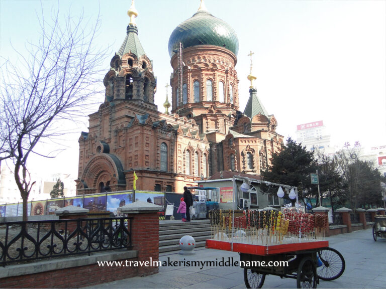 St Sophia cathedral in the background and a cart selling bing tang hulu (skewers of fruit coated in yellow and red candy) on the street.