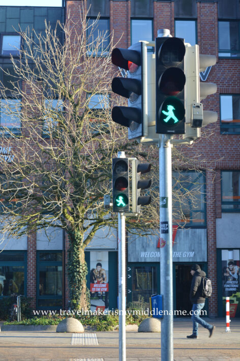 The green Ampelmänchen is a silhouette of a man seen from the side with a hat, feet a stride apart, and arms outstretchedin front, to indicate to the pedestrian to walk.