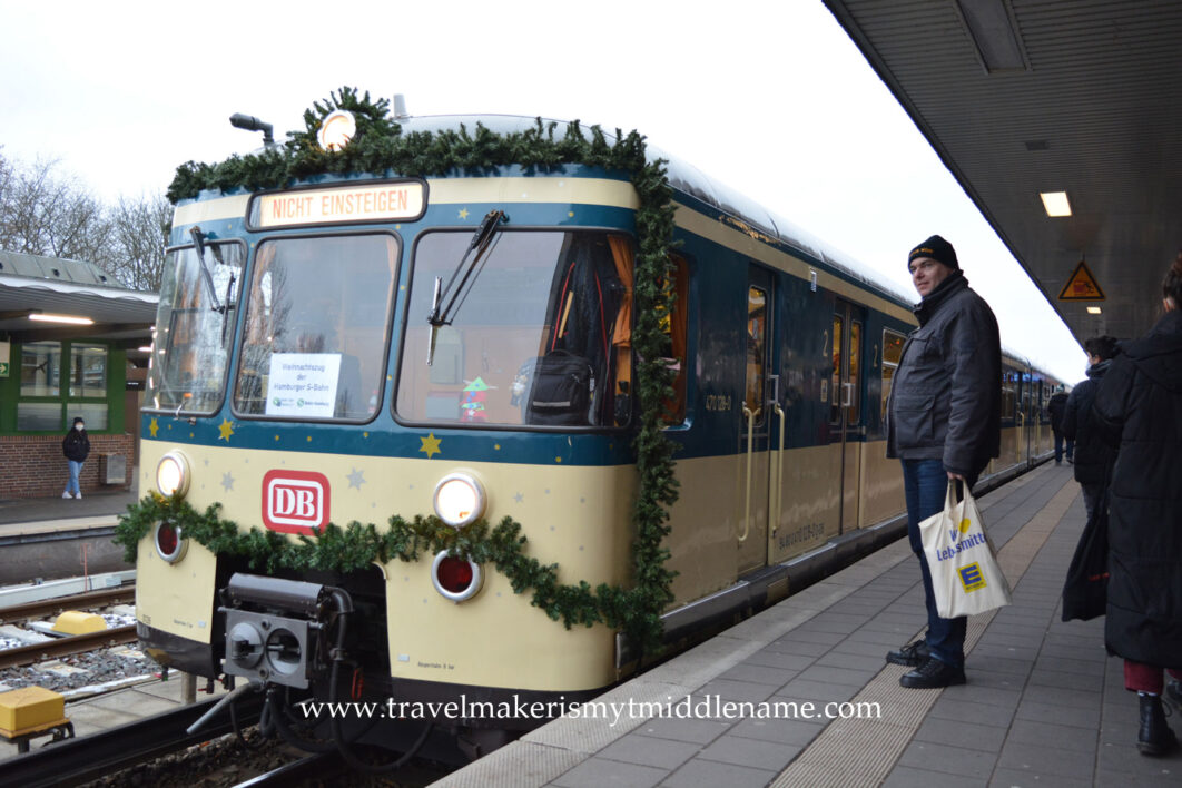 Outside the front of the Hamburg Christmas Train is decorated with green tinsel. A red DB logo is on the front.