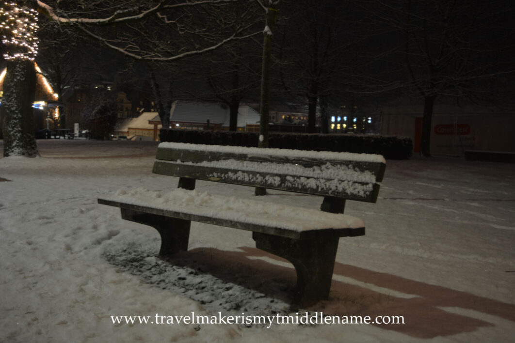 A snow covered park bench in Lübeck in the middle of December at night