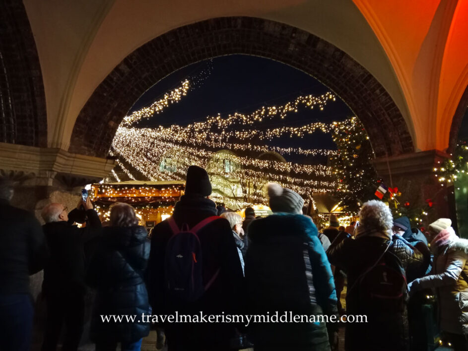 People under an arch walking into the Christmas market at night in Lübeck