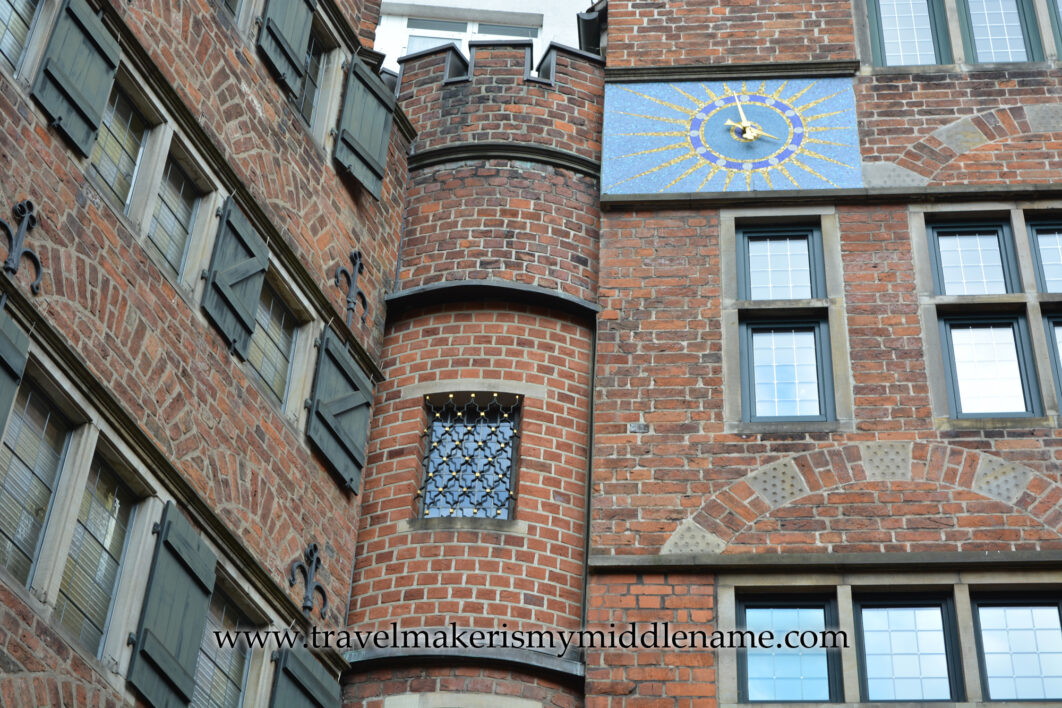 The red brick Haus des Glockenspiels or Glockenspiel House in Bremen, Germany. The blue and gold clock wall shows approximately 4pm.